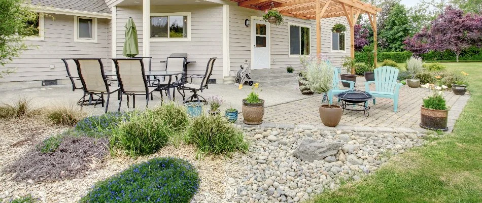 Landscape bed with rocks and plants in Highland Village, TX, by a patio and a pergola. 